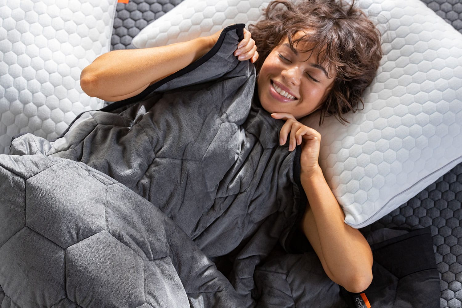 Woman laying down on bed and pulling a weighted blanket up
