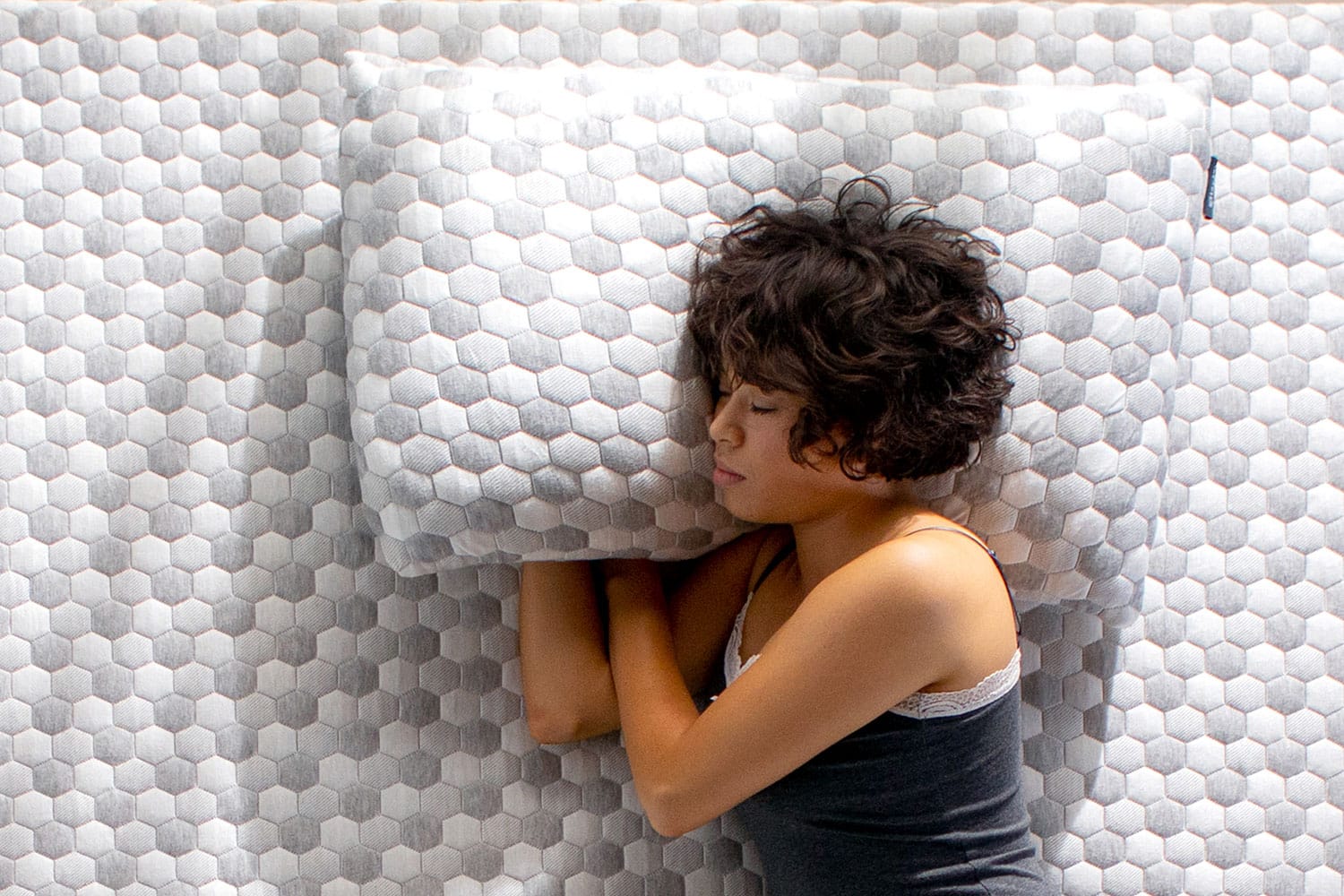 Woman sleeping on a mattress, resting her head on a Kapok Pillow
