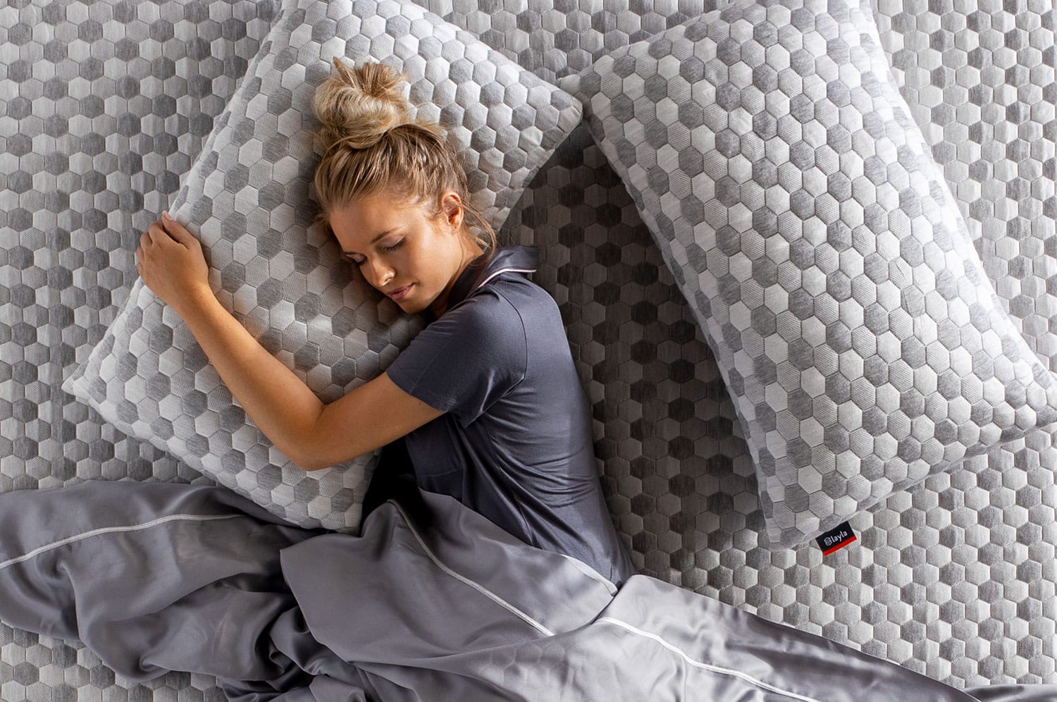Woman hugging Kapok Pillow while lying down on a mattress